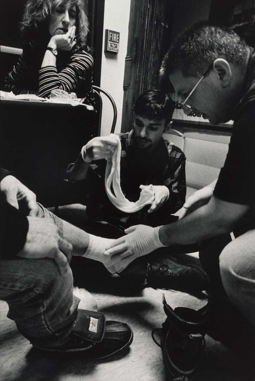 Boston (At the Boston Night Center, Toni Abraham, a nurse practitioner from the Boston Health Care for the Homeless program, supervises while nurse Jack Castro and Mark Lepore, a student from Boston University Medical School, bandage the badly infected foot of a homeless man. Often, homeless people will first present themselves to health personnel when they have serious problems with their feet. Swelling of the feet and legs, cellulitis, and skin ulcerations are common among people living on the street. Inadequate opportunities to bathe, ill-fitting and wet shoes, and exposure to the elements all contribute to medical problems. "When your feet don't work, you can’t do the things that you need to do," says one.)