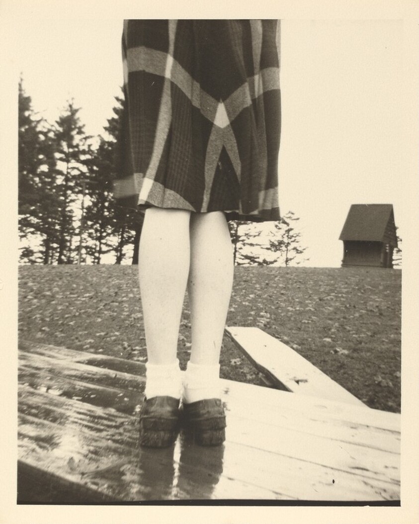 Untitled (Plaid skirt and legs on wood table)