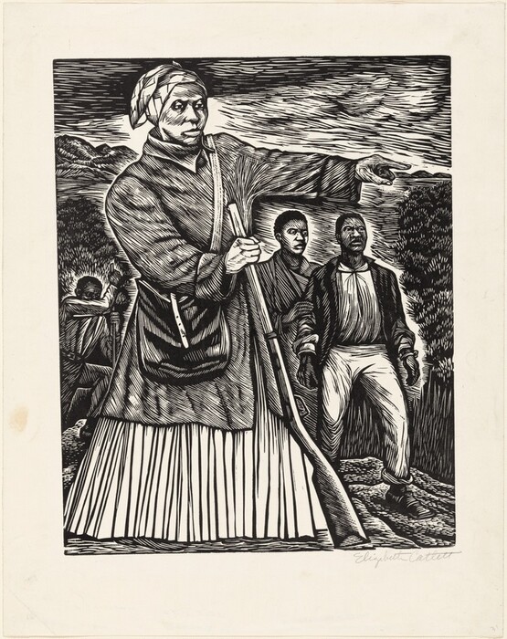 Printed with black against cream-white paper, a woman pointing to our right nearly fills this vertical linocut. Her body is angled slightly to our right, and she looks off in that direction with hooded eyes. She has wide cheekbones, a thin upper lip, full lower lip, and her mouth is closed over a pointed chin. Her head is covered in a patterned cloth, and she wears a knee-length coat over a long skirt. A knapsack hangs across her torso, and she braces the barrel of a rifle with her right hand, to our left, as she points with the other hand. Two people with short, dark hair stand behind her and to our right. The front person wears pants, square-toed shoes, and a jacket over a shirt. Bracelet-like objects on his wrists could be broken shackles. The other person touches that man’s arm. A fourth person digs in the background to the left. The ground, trees, hills, and sky are dense flicks, slivers, and strokes. The artist signed the sheet in the bottom right corner under the image, “Elizabeth Catlett.”