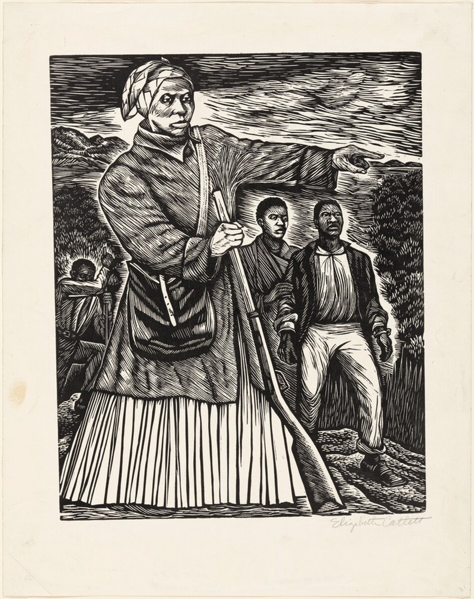 Printed with black against cream-white paper, a woman pointing to our right nearly fills this vertical linocut. Her body is angled slightly to our right, and she looks off in that direction with hooded eyes. She has wide cheekbones, a thin upper lip, full lower lip, and her mouth is closed over a pointed chin. Her head is covered in a patterned cloth, and she wears a knee-length coat over a long skirt. A knapsack hangs across her torso, and she braces the barrel of a rifle with her right hand, to our left, as she points with the other hand. Two people with short, dark hair stand behind her and to our right. The front person wears pants, square-toed shoes, and a jacket over a shirt. Bracelet-like objects on his wrists could be broken shackles. The other person touches that man’s arm. A fourth person digs in the background to the left. The ground, trees, hills, and sky are dense flicks, slivers, and strokes. The artist signed the sheet in the bottom right corner under the image, “Elizabeth Catlett.”