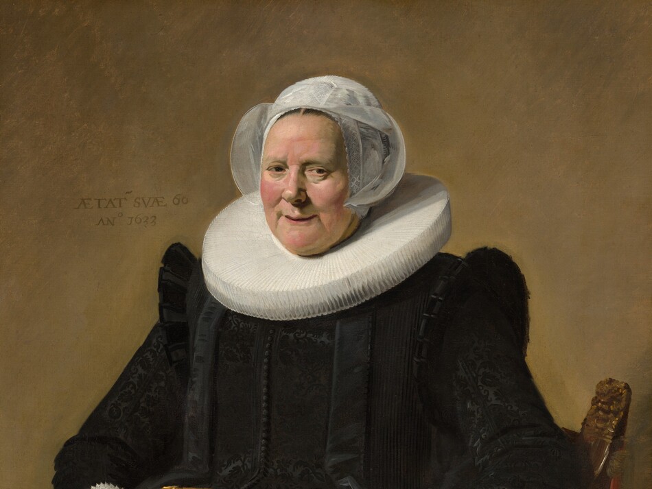 This vertical portrait painting shows a pale-skinned older woman wearing a full, long-sleeved black dress with a wide white ruff at her neck and white lace cuffs at her wrists. She sits in a curving, low-backed wood chair against a pale brown background. Her body and the chair are angled slightly to our left, and she looks directly at us. She has small eyes, pink, rounded cheeks, and a wide chin. Her lips are parted in a slight smile, and her hair is covered by a starched, sheer white cap that flares at the sides. The ruff around her neck is gathered in accordion-like, narrow figure-eight folds, and it extends flat and stiff, nearly to her shoulders. Close inspection reveals that the dress is woven with a black-on-black brocade pattern and has a line of small black buttons down the front. She holds a small brown leather book tooled with gold ornament in her right hand, on our left, and her other hand rests on the arm of the chair. She wears a gold ring on each hand. An inscription is painted to our left of her head: “AETAT SVAE 60 ANo 1633.”