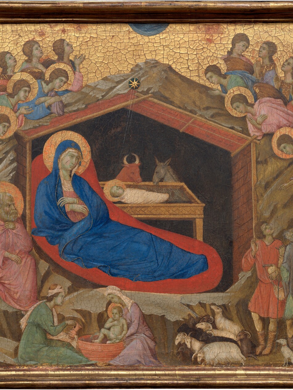 This horizontal painting is made up of three parts: in the center square panel, a woman reclines under a wooden shelter set into a rocky cave, which is surrounded by angels, and narrower wings to either side are each occupied by a standing man. All the people have pale skin, which is tinged with faint green. The three panels are joined with a gold frame, and the gold background behind the central scene and the men in the side panels are covered with a noticeable network of cracks. In the central panel, a cobalt-blue robe nearly envelopes the reclining woman’s body; this is Mary. It covers her head and falls open where she crosses her wrists over her chest to show a pink garment underneath. A flat gold halo encircles her head ,and her body is surrounded by a field of crimson red, almost like an aura. She rests under a wooden structure with a pitched roof, which is surrounded by craggy, barren rock. A swaddled infant lies in a rectangular, tray-like manger. The infant’s head is also surrounded by a gold halo. Fine gold rays emanate down into the structure from a star just above the peak of the roof. A bull and a donkey look down at the baby from the far side of the manger. The interior of the structure behind them is black. In a smaller scale, two women wash a haloed infant in a tub in front of the rocky cave near the lower left corner of this panel. A man with a white beard and hair sits to our left of Mary, holding a pink cloak at his throat and looking toward the infant. Above and around the rocks, seven winged and haloed angels cluster on each side. One angel to the right presents a scroll with black writing to two men accompanied by a dog and several sheep in the lower right. The man in the panel to the left, Isaiah, has a gray beard and long, wavy hair, and he wears a lilac-purple cloak draped over a coral-orange robe. In his right hand, on our left, he holds an unfurled scroll with large black lettering. His other hand is raised with one finger pointing upward. He looks to our left, away from the central scene. On the right, Ezekiel, echoes Isaiah's pose. Ezekiel holds an open scroll with his left hand, on our right, and his other hand is raised. He also wears a coral-colored robe, but his is overlaid with a blue cloak. His receding hair is short and brown, as is his beard. Like Isaiah, he takes up most of the height of the panel and gazes to our left, toward the central panel.