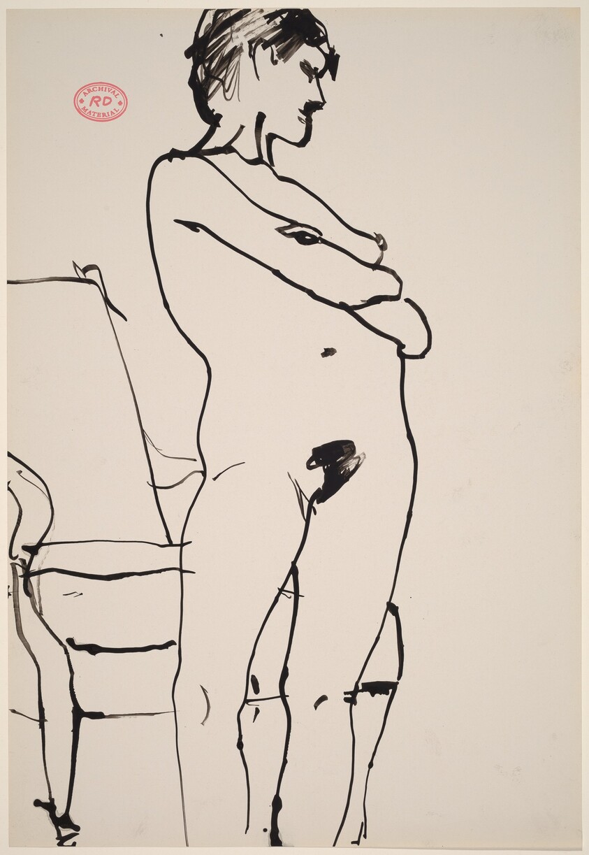 Untitled [female nude standing in front of an armchair]