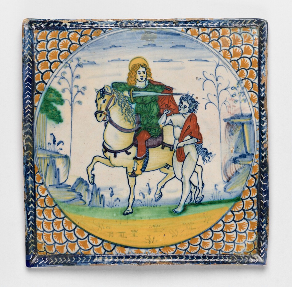 This is a painting of a medieval scene on a ceramic tile. The tile features a central image of a figure on horseback dressed in a green robe, reaching out with a red cloth towards another figure beside the horse. This second figure is on foot, draped in a similar red cloth. The horse appears dynamic and detailed, standing on a grassy landscape with a few stylized trees and architectural elements in the background. The outer edge is adorned with an intricate repeating pattern in orange tones, while the edges of the tile display a blue border with geometric designs. This is in the style of traditional Maiolica ware, a type of tin-glazed pottery.