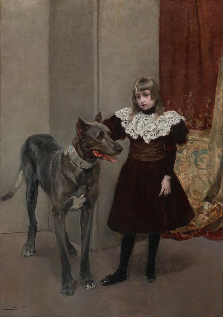 This painting shows a young girl standing beside a large dog. The girl has a fair complexion and straight brown hair that falls on her shoulders. She is wearing a dark burgundy dress with a white lace collar, black stockings, and shoes. She looks directly at us. The dog to the left reaches almost to her shoulder and has a light gray coat. Its mouth is slightly open, revealing a pink tongue and the tips of white teeth. The background is mostly plain gray walls, but on the right side there is elegant drapery in shades of deep red and gold with intricate teal designs.