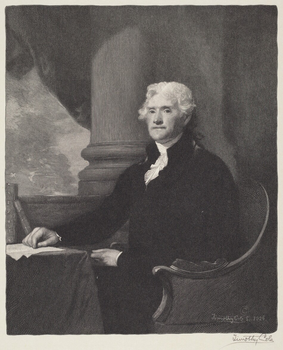 The image shows a man seated at a table. He is facing forward but turned slightly to the side, with his right hand resting on the table. The man has a prominent face with defined features and white curly hair that falls to his neck. He is dressed in formal attire, including a dark coat and a white cravat at his neck. His left hand is partially visible near his lap. The background features a large architectural column to his right, and a dark curtain or drapery occupies the space behind him. A table covered with a cloth resting on his right holds a paper and ink set.