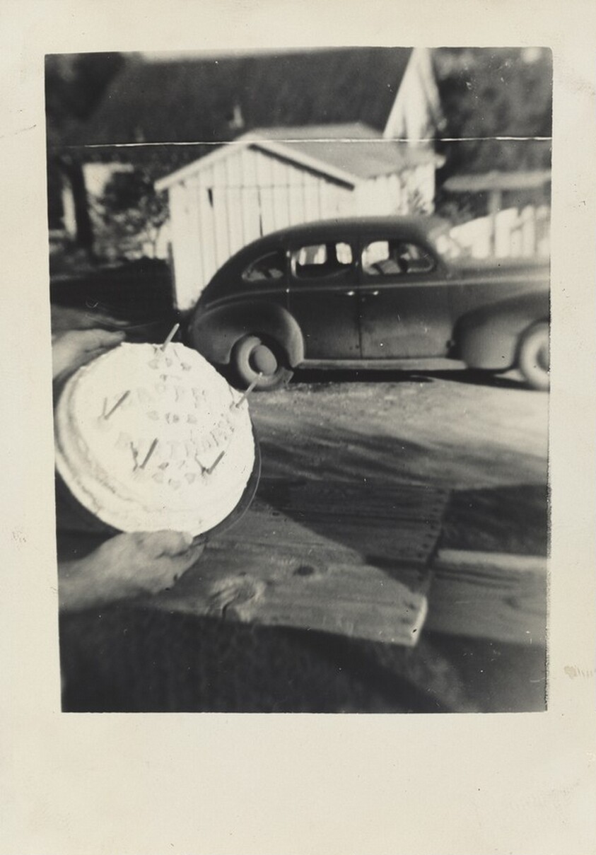 Untitled (Cake held in foreground with car behind)