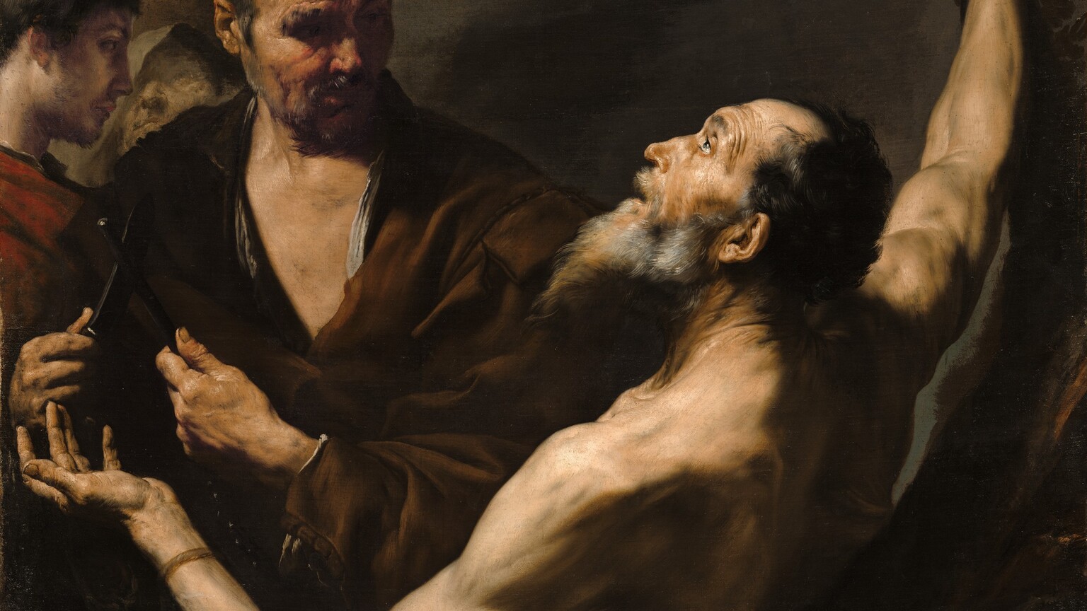 A group of four men with pale skin, shown from the waist up, almost fill this square painting. Light pours onto the scene from the upper left and falls across the upturned face of the bearded, bare-chested man, Saint Bartholomew, who is situated with his back facing us and his arms spread wide. In the top right corner, his right wrist is lashed to a pole that extends off the top edge of the painting. His other arm is bent at the elbow near the lower left corner, and he holds that hand palm up. His profile, facing our left, is bright against the shadowed background. His mouth is slightly agape, and his eyebrows are raised as he looks up toward the light that bathes his lithe, muscular body. His long beard is streaked with gray, and he has receding black hair. A second, broad-shouldered man, draped in a brown cloak, stands facing us behind and just to our left of Saint Bartholomew. The younger man holds a knife in one hand resting against a black, rod-like sharpener held in the other. He turns his head to gaze at Saint Bartholomew, his eyes deep in shadow. He also has a furrowed brow and a craggy, ruddy complexion. Two more men stand behind him, to our left, filling the left side of the painting. The man on the far left has smooth skin, a trimmed beard, and short brown hair. He stands in profile looking to our right and wears a cranberry-red cloak. Barely visible beyond him, to our right, is a man wearing a gray-green hood hiding half his face. His features are loosely painted and faint, but he also looks up, either toward the young man or the light from above. All four are surrounded by deep shadows against a brown background.