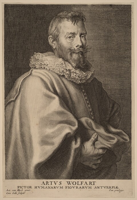 In the image, a person is shown from just below the chest up, with a focus on the upper body and head. The individual is in a slight three-quarter turn to the left, with hands draped in the garment in front of them. The person has a full beard, mustache, and well-groomed hair that is slightly wavy and receding at the temples. They are wearing a garment with a large lace collar and decorative buttons. There is no visible jewelry, and the hands appear to be holding the cloak around them. The background consists of a textured, dark space, which does not distract from the figure.