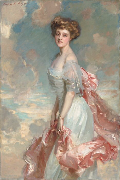 A young woman with pale, peachy skin, wearing a long, silvery blue dress with a rose-pink train looks out at us in this vertical portrait painting. She stands in front of a topaz-blue sky dotted with puffy white clouds, which are shaded with shell pink and light lilac purple. Her body faces our left in profile and she turns her smiling, oval-shaped face to us. She leans her torso slightly forward. Her light brown hair is loosely piled on her head. Her gray-blue eyes are framed by delicate brows, and she has an aquiline nose, rosy cheeks and lips, and a long, elegant neck. Light glints off the dress she wears, suggesting is silk or satin. It has a low, straight neckline and the short, fluttery sleeve we can see falls off her shoulder. A long, billowing swath of light pink fabric is attached to the back of her dress, possibly with a large bow, and it drapes in lively folds down and around the front of her skirt. She holds it lightly with both hands at her thighs. She wears a thin gold bracelet on her left wrist, closer to us, and a silver ring on the third finger of that same hand. The portrait is loosely painted, especially in the clothing, so the texture of the brushstrokes is visible in many areas. The artist signed the work with brick-red paint in the upper left, “John S. Sargent” and dated the upper right, “1907.”