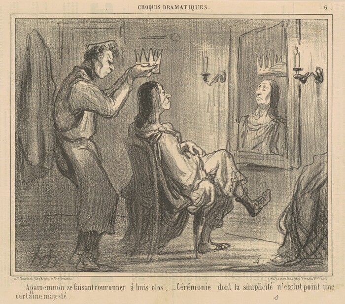 The image shows two men in a room. One man is sitting in a chair with his legs crossed and looking at his reflection in a mirror, while the other man stands behind him, placing a crown on his head. The seated man's reflection in the mirror shows elongated facial features, dark long hair, and he is wearing a robe. The standing man has curly hair and a focused expression, wearing a long-sleeved shirt and trousers. A coat or fabric hangs on the wall behind him, and there is a lit candle sconce on the wall.