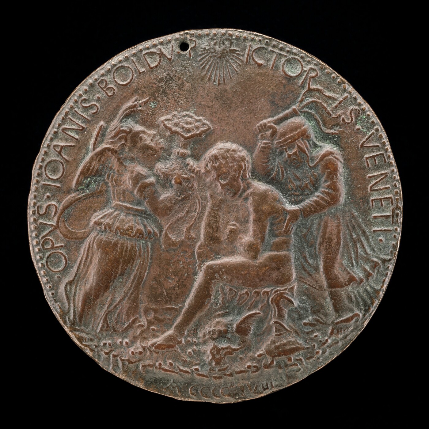 The image shows a relief on a circular medallion featuring three human figures. The central figure is seated, while the two flanking figures are standing and interacting with the central figure. The sculpture is crafted from a darkened material, likely bronze or copper, and has intricate details on the figures and edges. There is text on the edges of the medallion and a small hole at the top. The craftsmanship suggests a historical or classical theme.